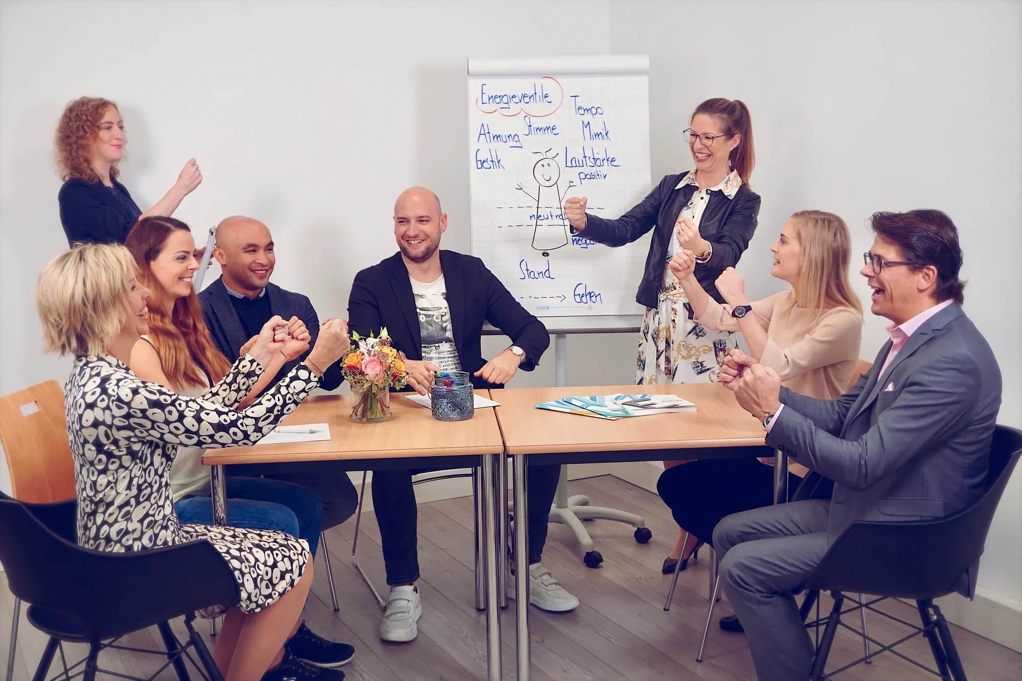 A seminar group at a table, with a trainer at a flipchart in front of them